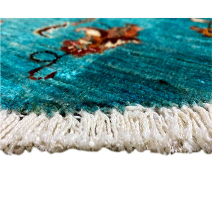 Close-up of the carpet edge: turquoise pile with a white-cream fringe trim.