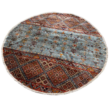 Round wool rug with a textured look, a blue-gray pattern, and a border in brown, orange, and reddish brown