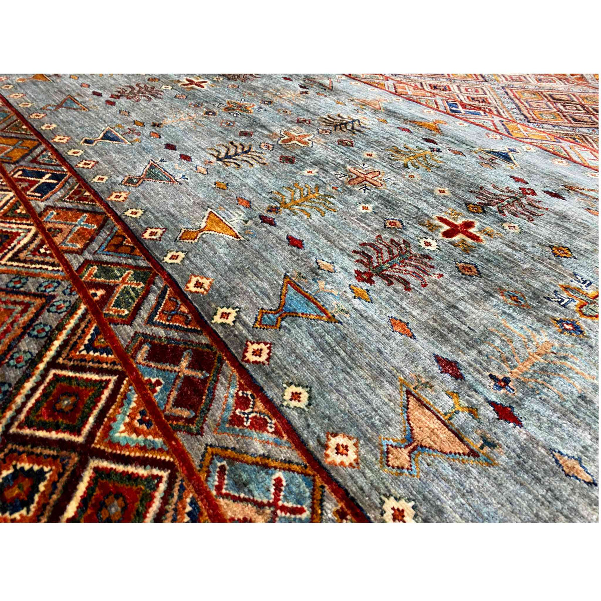 Close-up: gray-blue wool rug with colorful crosses and ornaments, rectangular border
