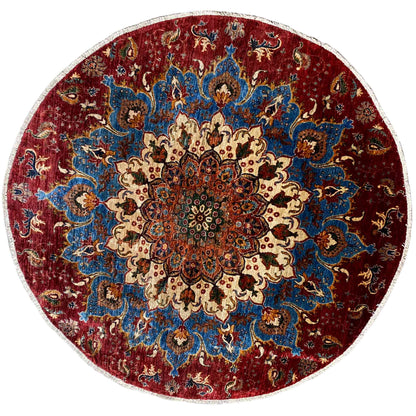 Round wool rug with a red and blue ornamental pattern, cream-colored details