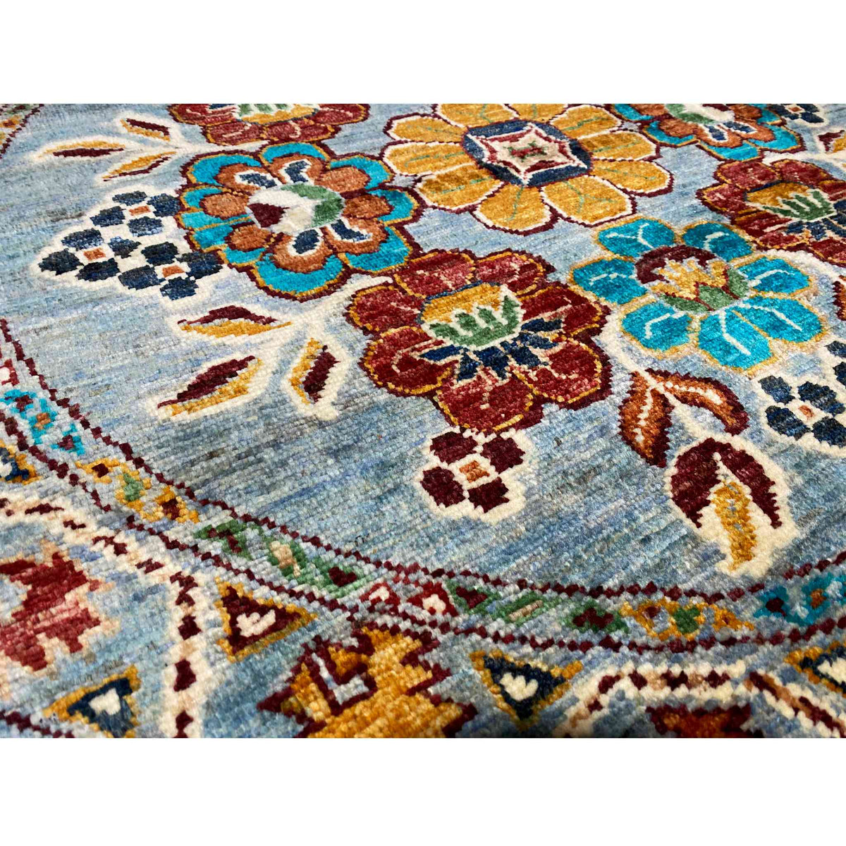 Close-up of a Khorjin wool rug: blue-ground floral pattern with colorful ornamental details