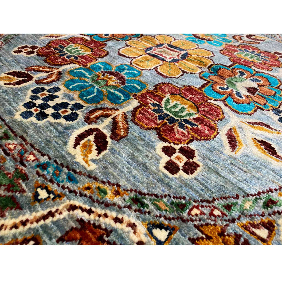 Close-up of wool rug: colorful floral motifs on a blue background with an embroidered look