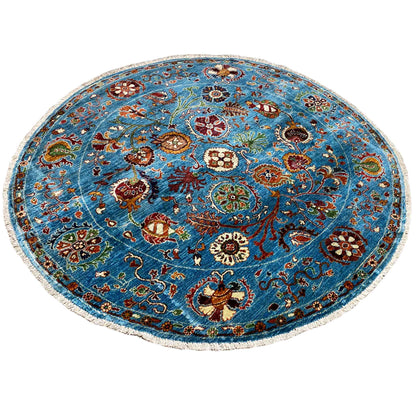 Blue round wool rug with a multicolored floral motif and curved patterned border