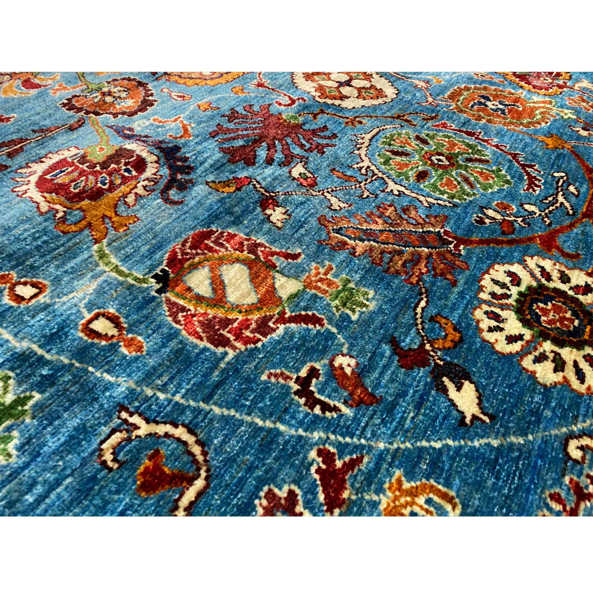 Close-up: blue wool rug with multicolored floral motifs and woven texture
