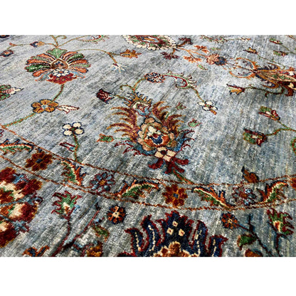 Close-up of a Khorjin wool rug: light blue-gray pile with colorful embroidered motifs