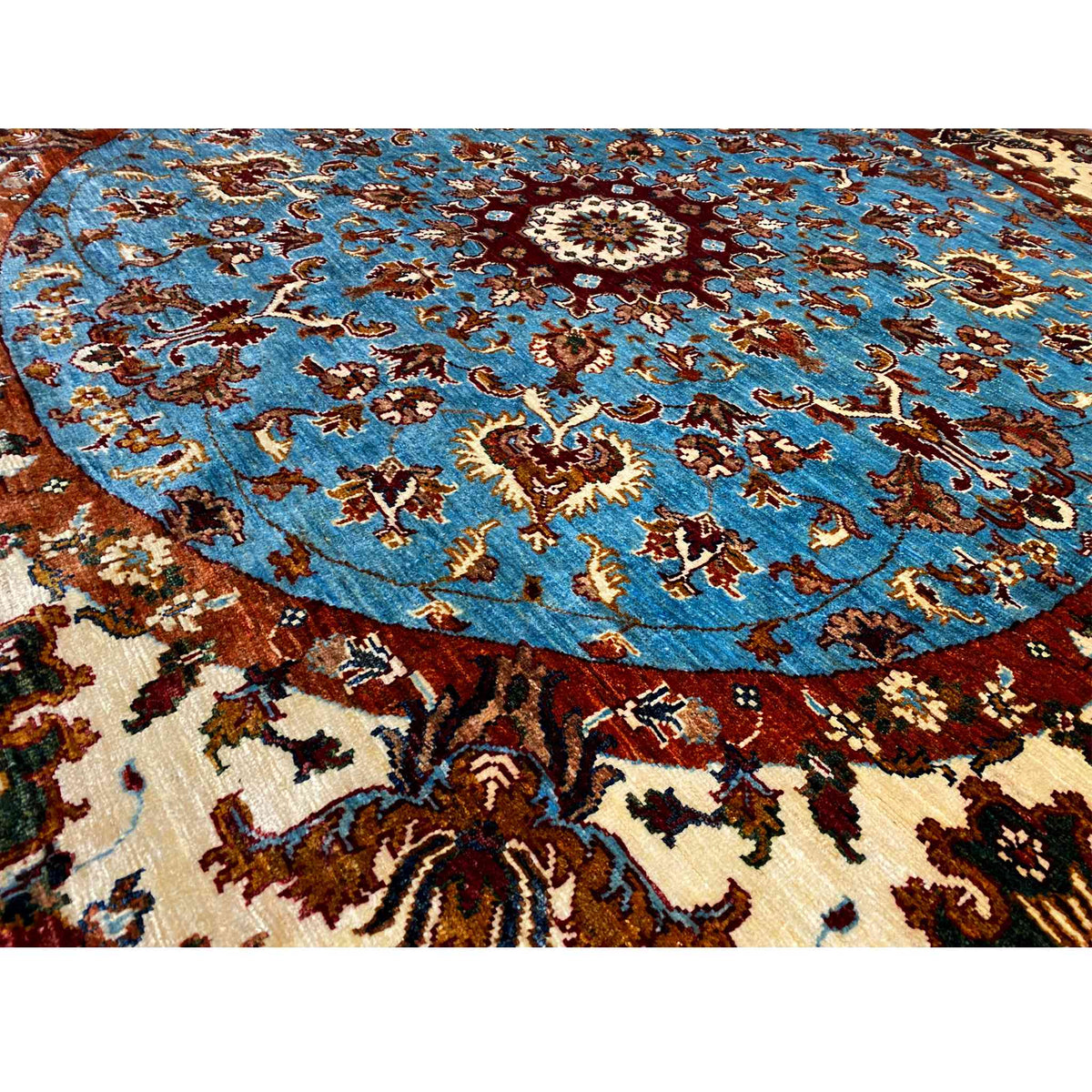 Close-up of a wool rug: blue field with cross and vine ornaments in beige and brown