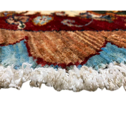 View of a wool rug edge with pile, blue-brown patterns, and a white fringed finish