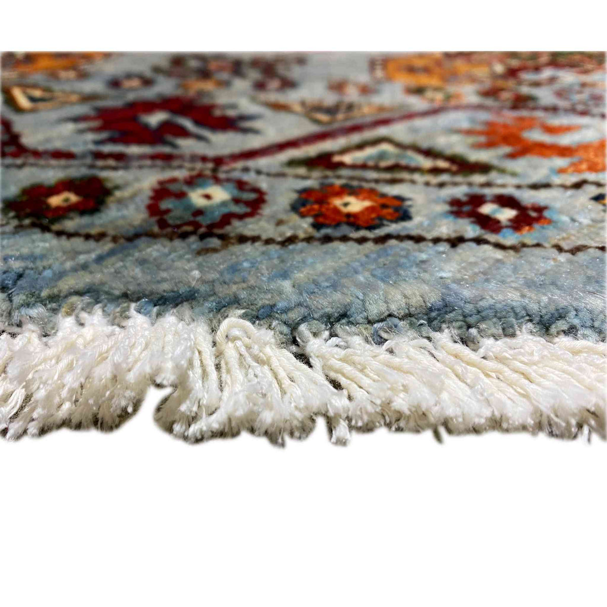 Rug edge with fringes and pile, multicolored pattern on a light gray background