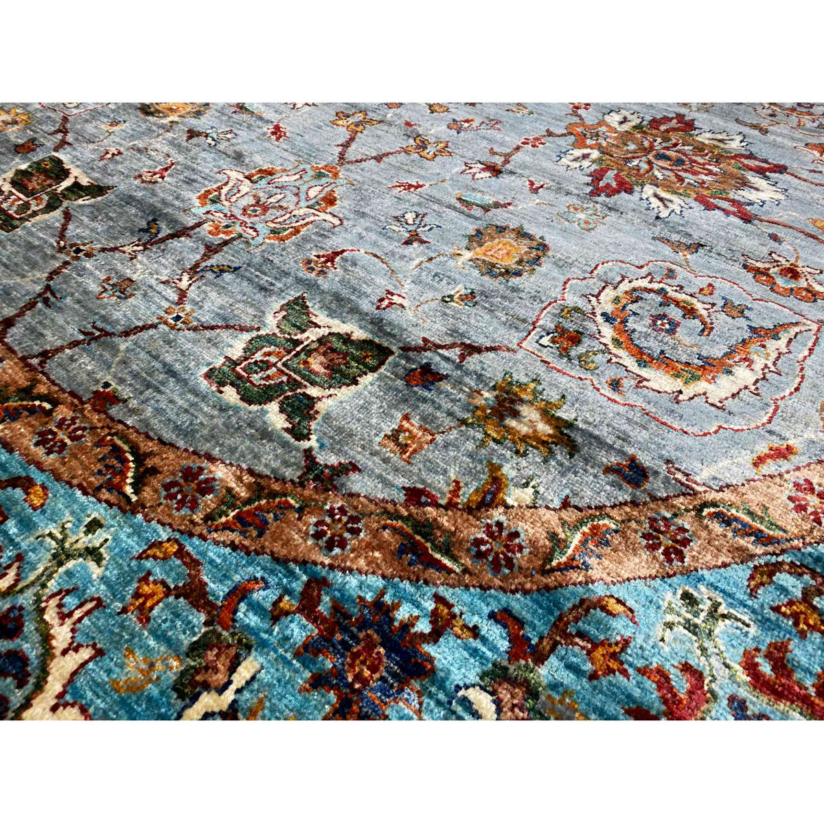 Carpet detail: gray pile with colorful ornaments, a golden-brown frieze and turquoise border