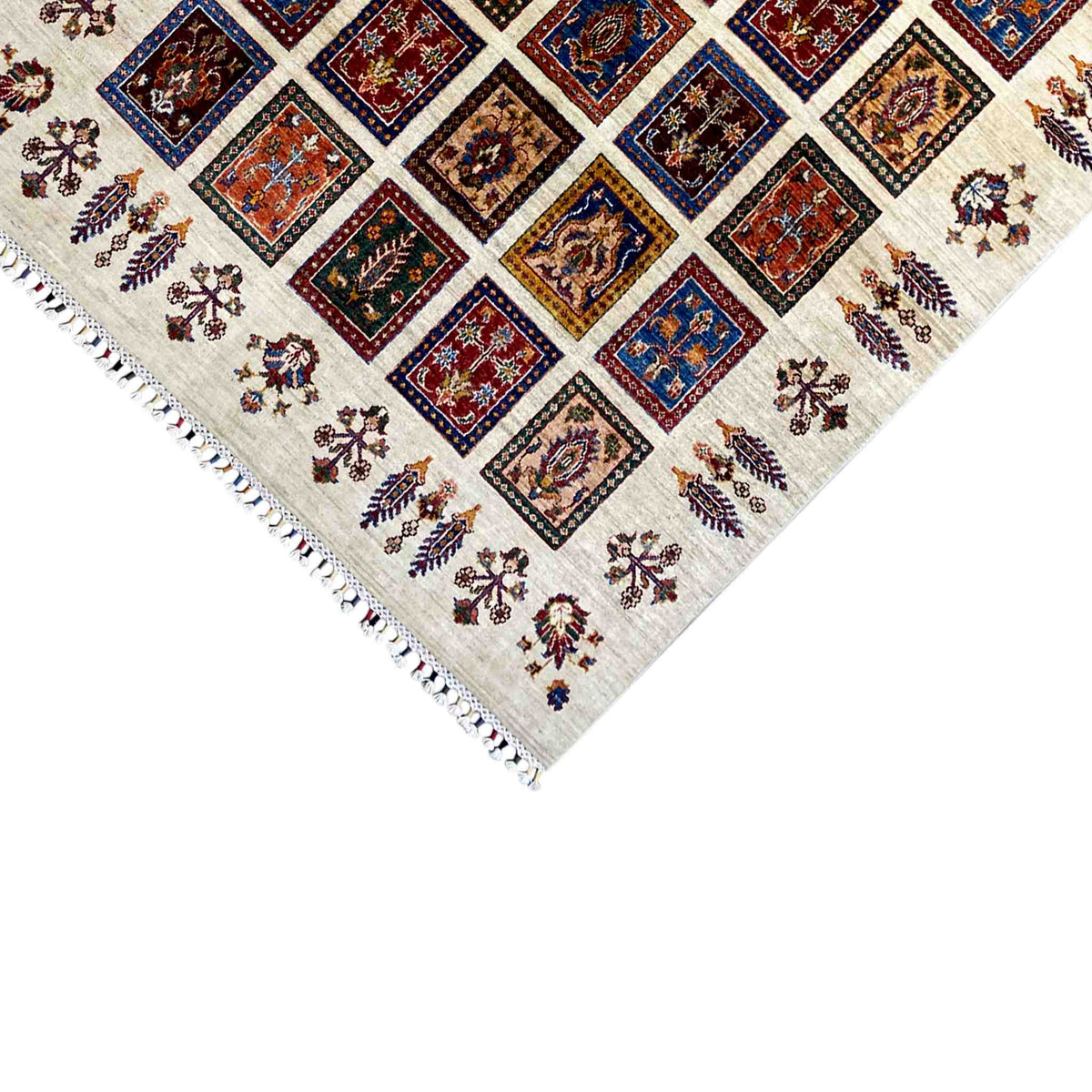 Close-up of the rug corner: fringed edges, a cream-colored base, and square motifs