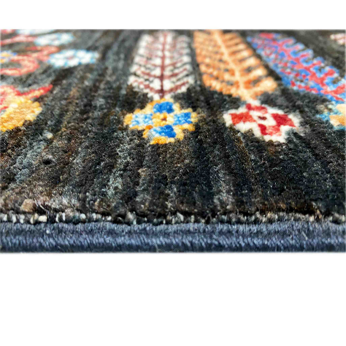 Close-up of the carpet pile and fringe along the edge, multicolored patterns on a dark background