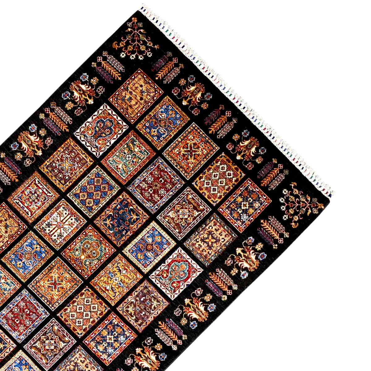 Corner of a wool rug with fringe and a wide border pattern, black background