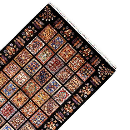Corner of a wool rug with fringe and a wide border pattern, black background