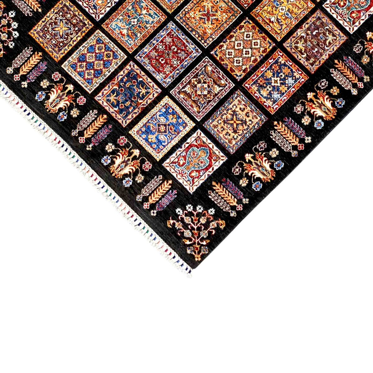 Corner view of a wool rug with fringed edging and colorful tile motifs on a black background