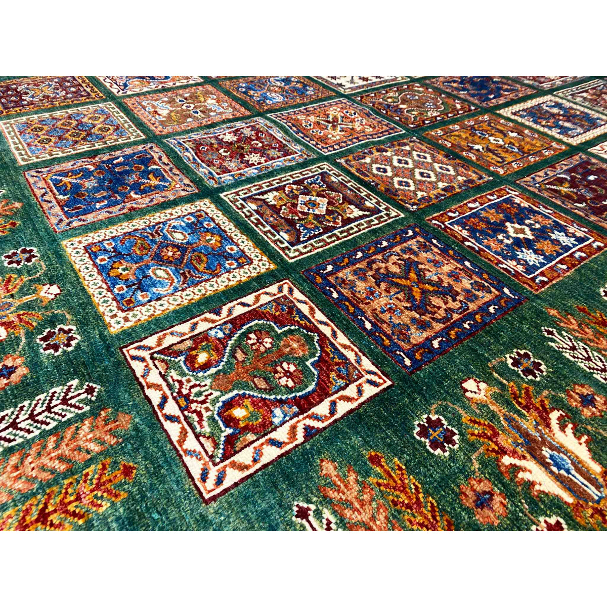 Close-up of a hand-knotted Khorjin rug: green surface with colorful decorative squares