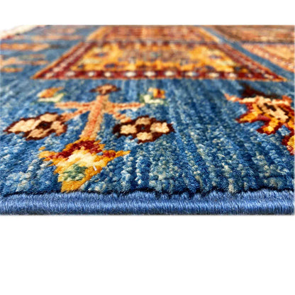 Carpet detail: handwoven wool with a blue pile and colorful ornaments, fringes along the bottom