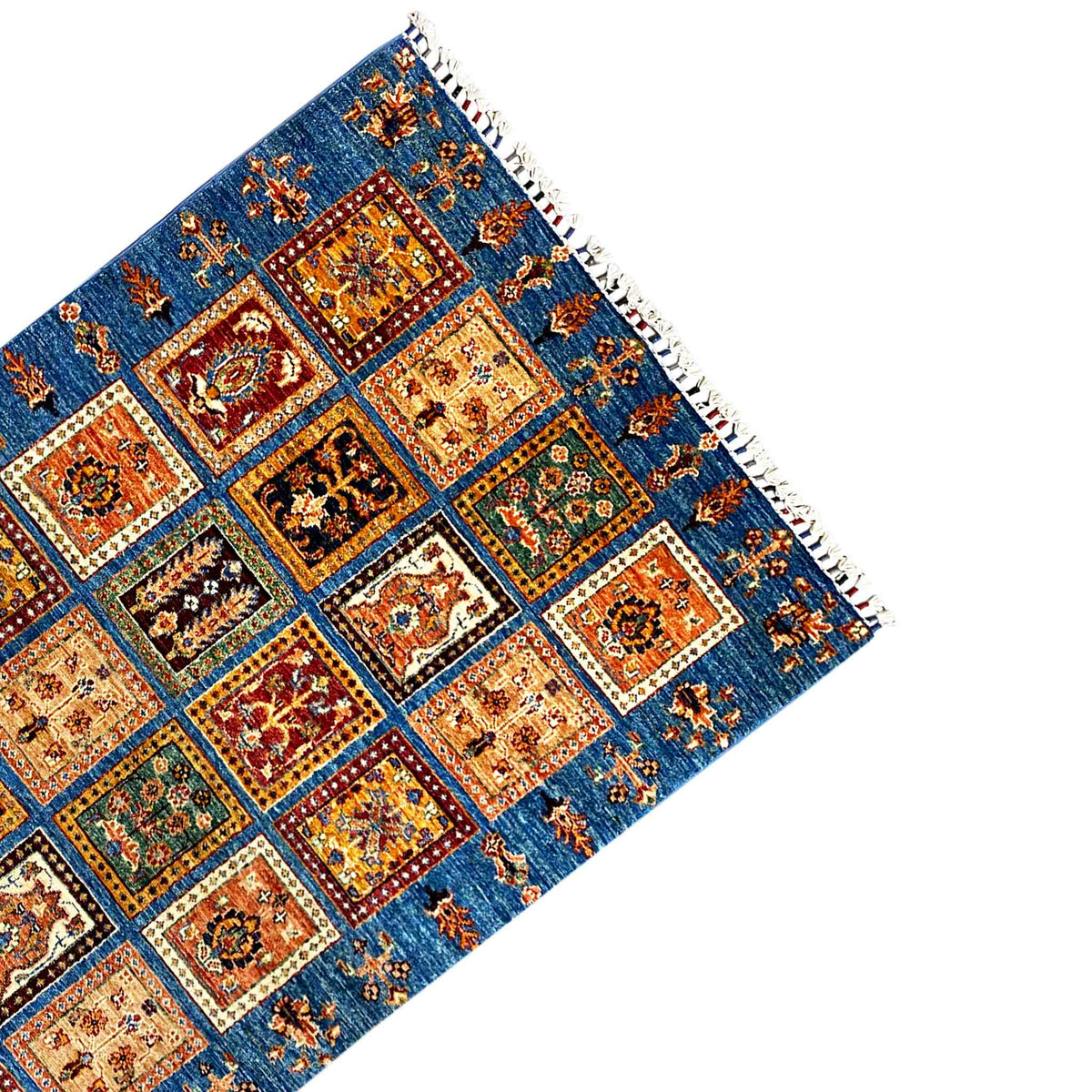 Corner view of the rug: blue pattern with tiled squares and white fringes