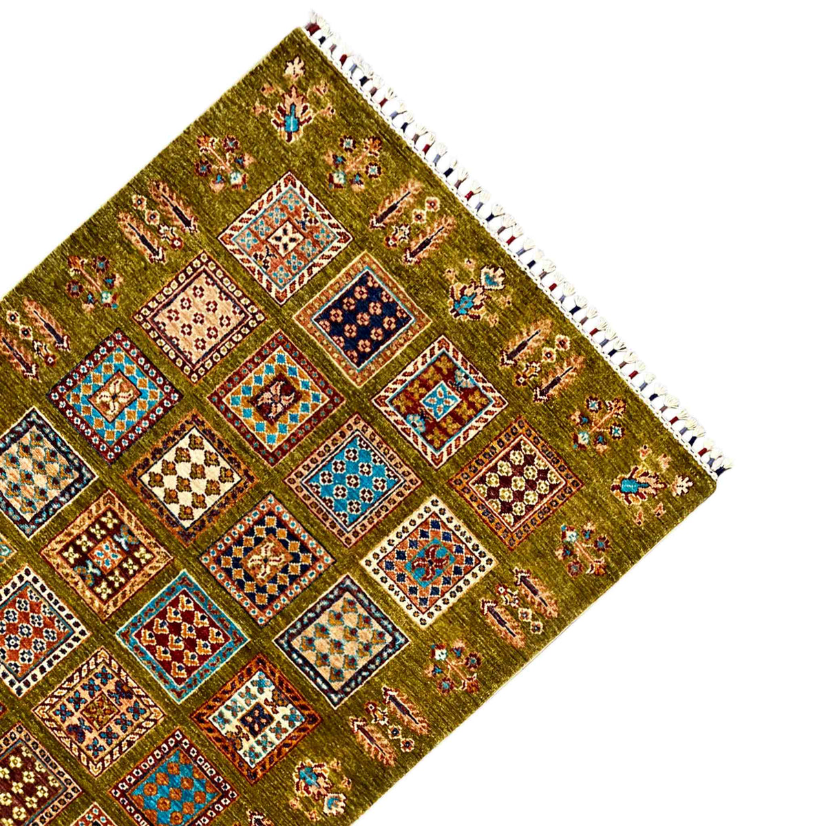 Corner of an olive-green wool rug with colorful patterns and white fringes