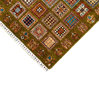 Olive-green wool rug in the corner with a colorful pattern and white fringes