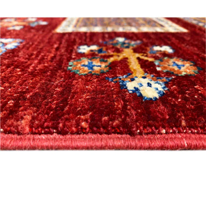 Close-up: deep red wool rug with colorful floral motifs and dense pile.