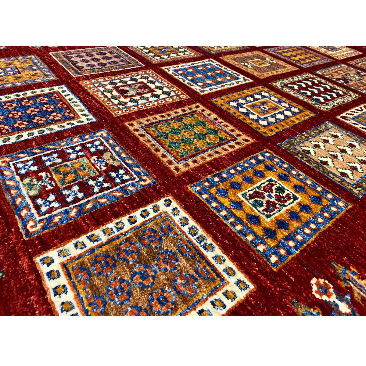 Close-up of the carpet pattern: deep red background with multicolored squares and diamond shapes.