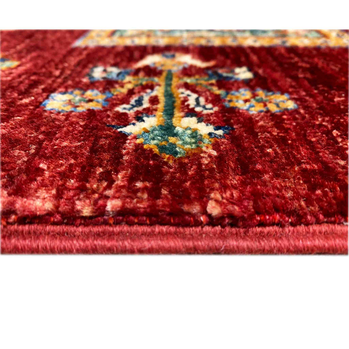 Close-up: deep red wool rug with a colorful medallion and uniform pile texture