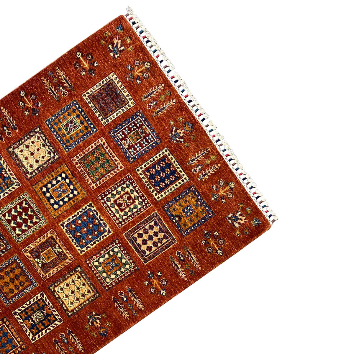 Brick-red wool rug with small ornaments, a white zigzag border, and fringe at the corner.