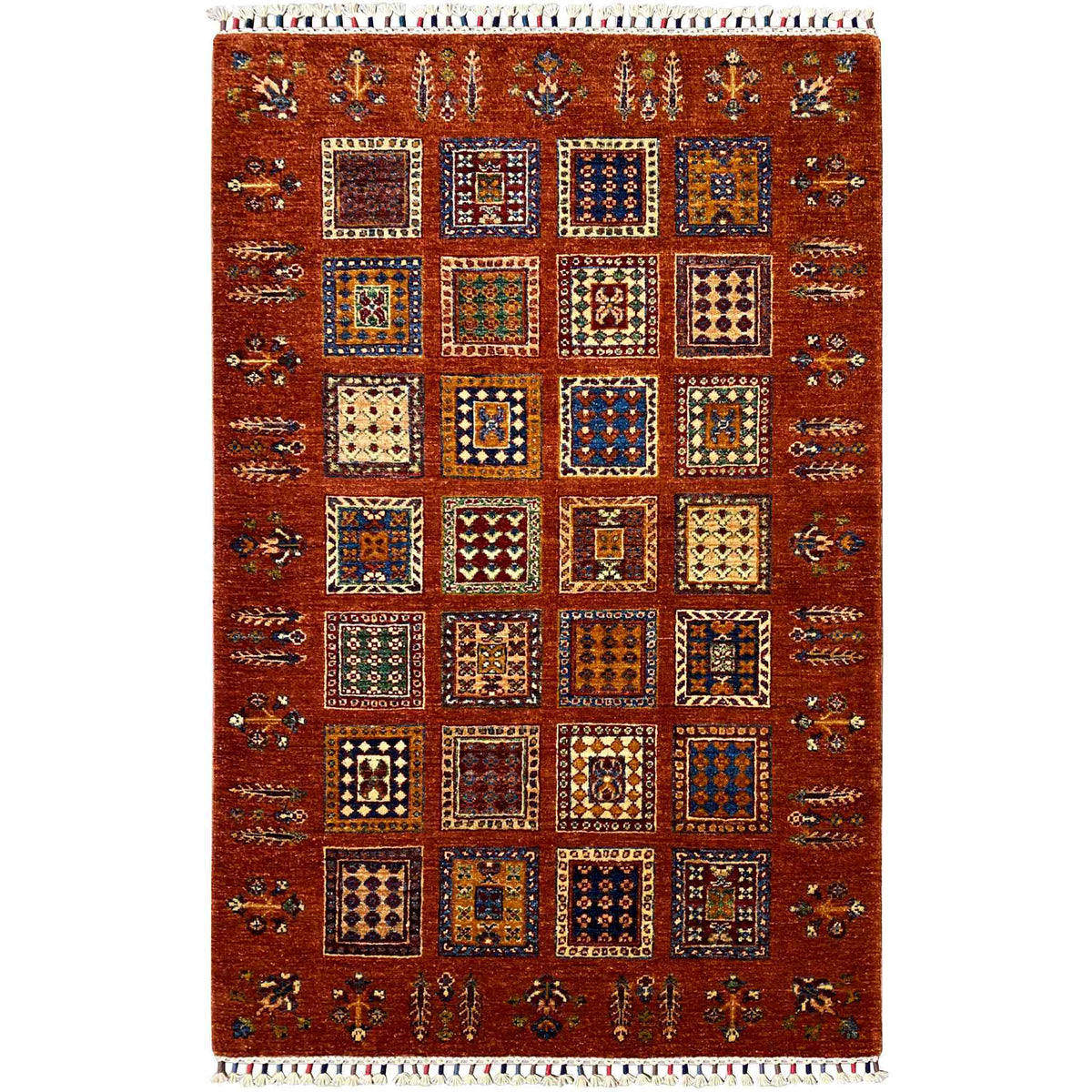 Brick-red wool rug with square vintage ornaments and fringes along the edge, rectangular.