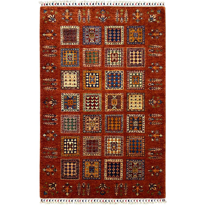 Brick-red wool rug with square vintage ornaments and fringes along the edge, rectangular.