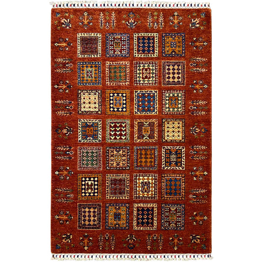 Brick-red wool rug with square vintage ornaments and fringes along the edge, rectangular.