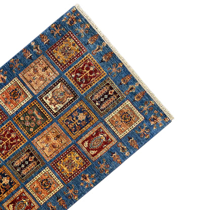 Rug corner: blue Khorjin rug with square ornamental panels and beige border fringe