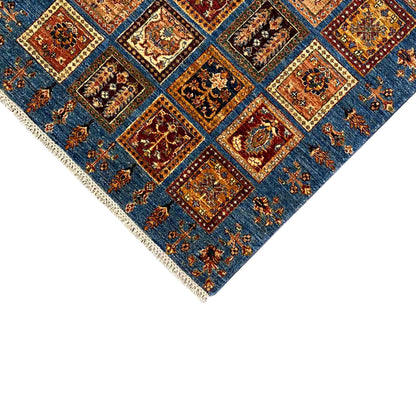Close-up of a rug edge: blue panels with patchwork squares and beige fringes