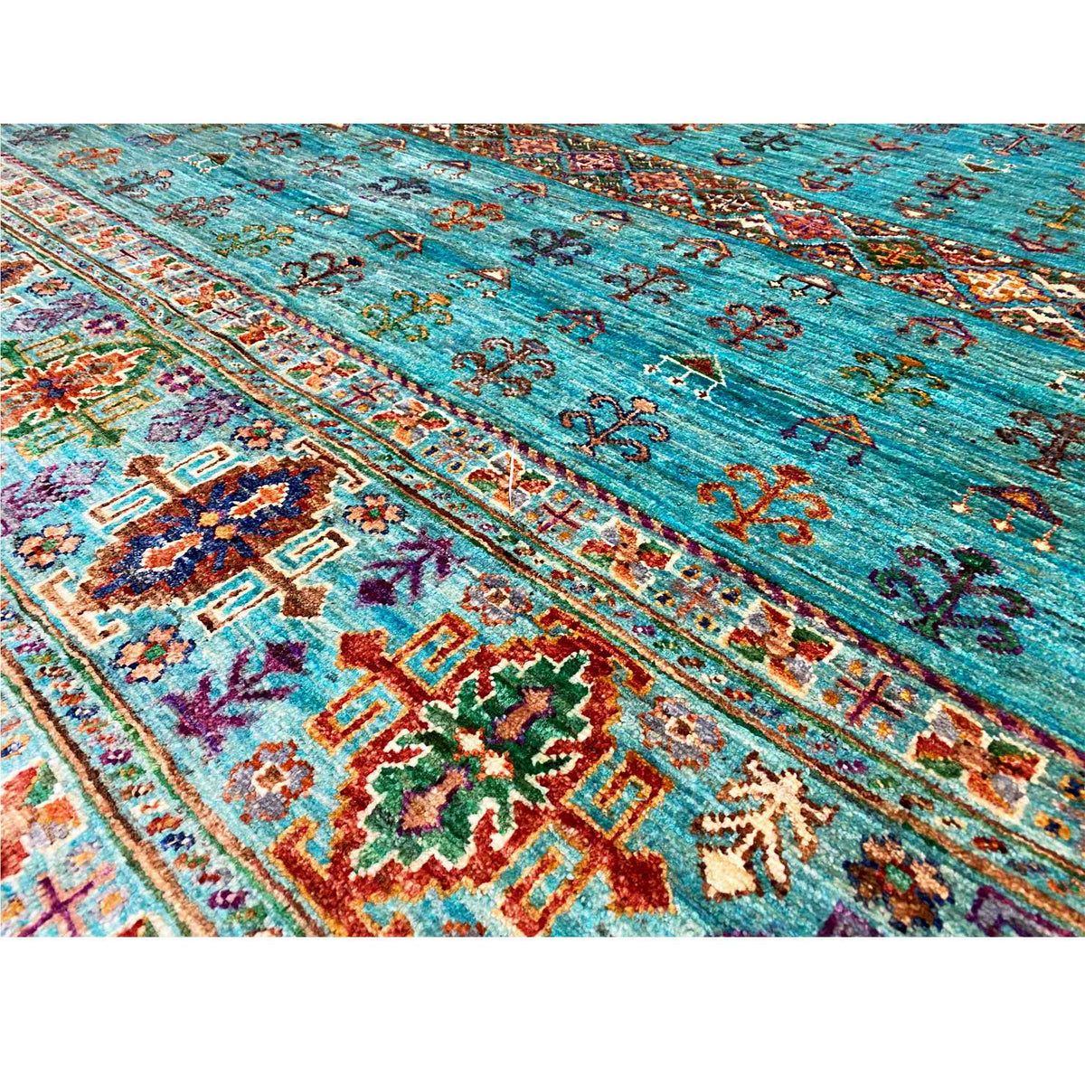 Carpet detail in petrol blue with ornamental friezes, colorful cross and floral motifs