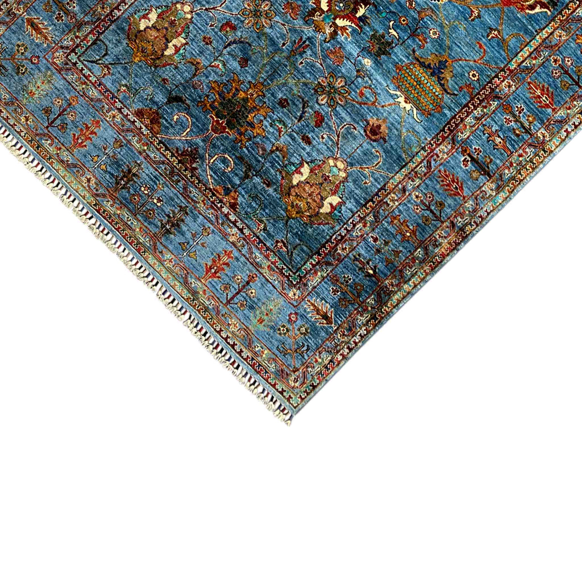 Corner of a blue Khorjin rug with floral motifs and fringe