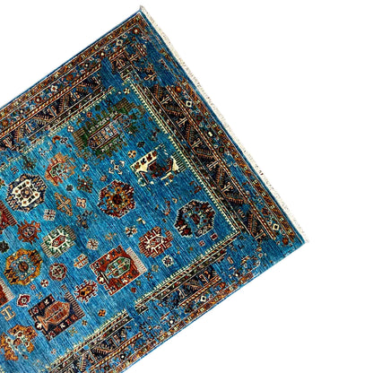 Corner view: blue carpet with an all-around border, rounded pattern area, and fringes