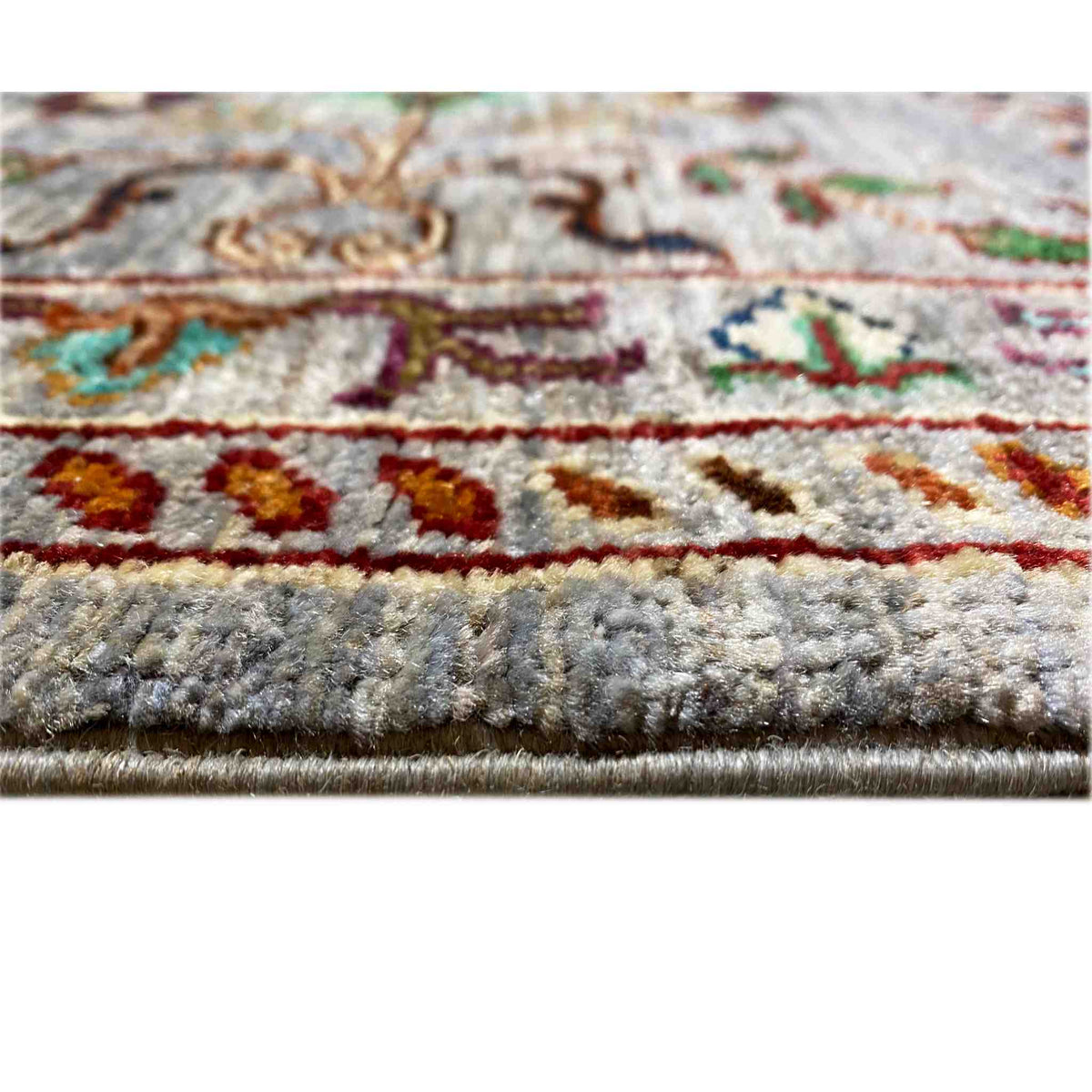 Detailed view: gray rug with a multicolored border and fringed edge