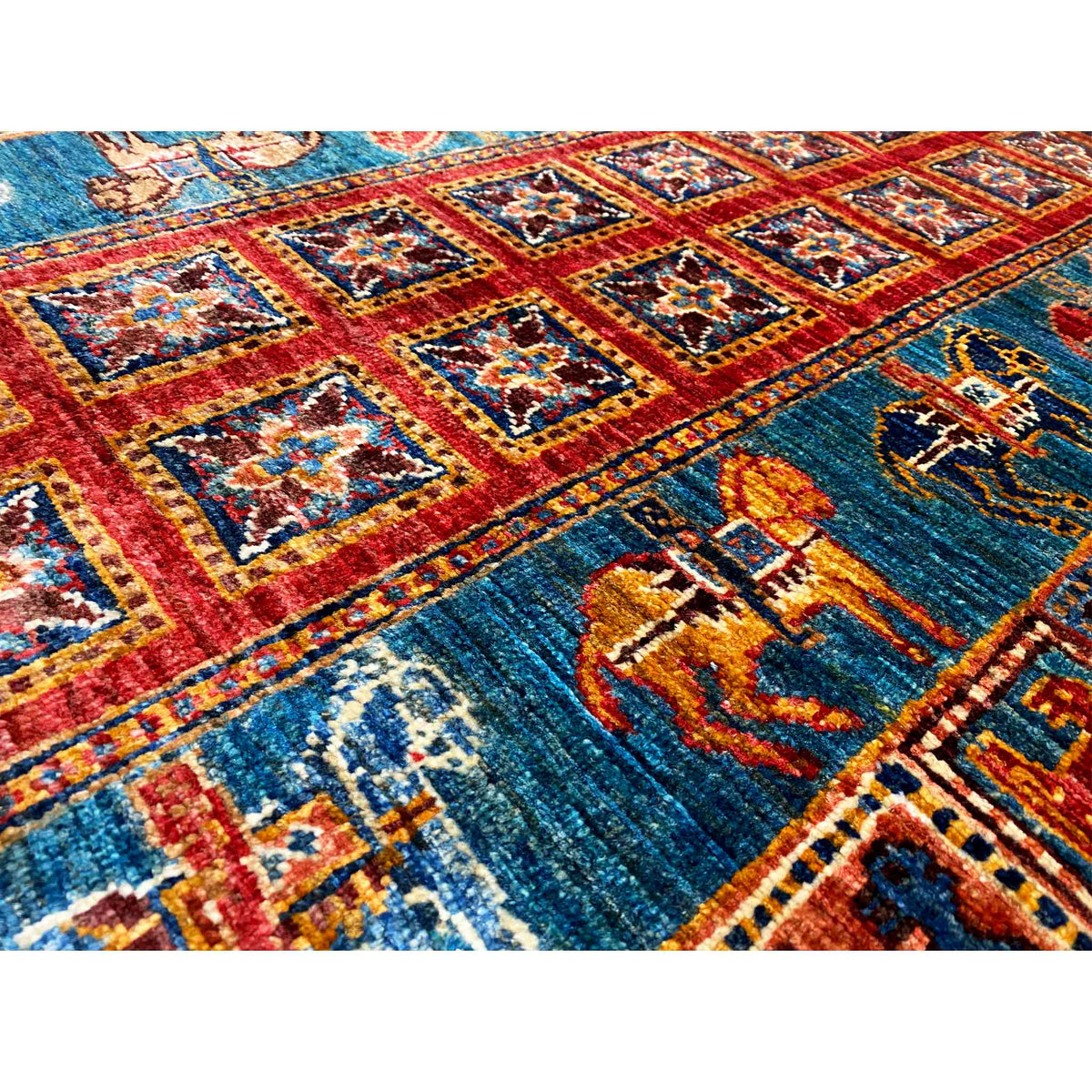 Close-up of the woven rug pattern: blue, red, yellow embellishments and animals