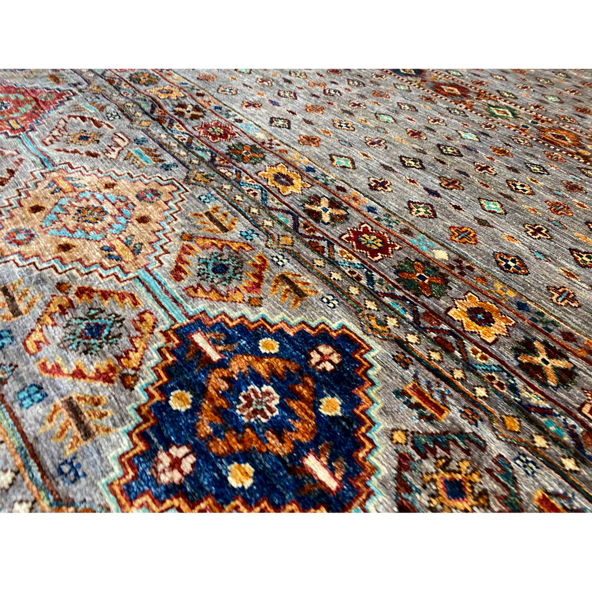 Hand-knotted Khorjin rug: close-up detail with dense patterns in blue, orange, and gray.
