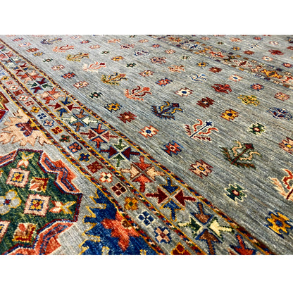 Close-up: colorful embroidered patterns on the light gray pile of the Khorjin rug