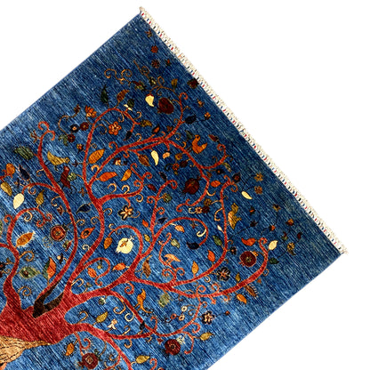 Close-up corner: tree of life vines on a blue background with colorful embroidery and fringes