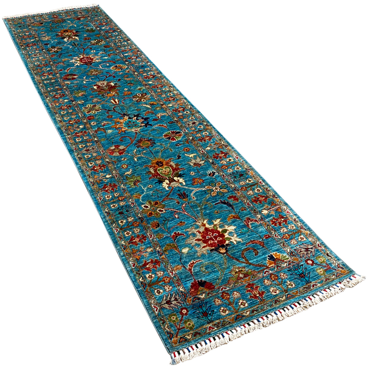 Hand-knotted runner from an angle: blue rug pattern with vines and fringes