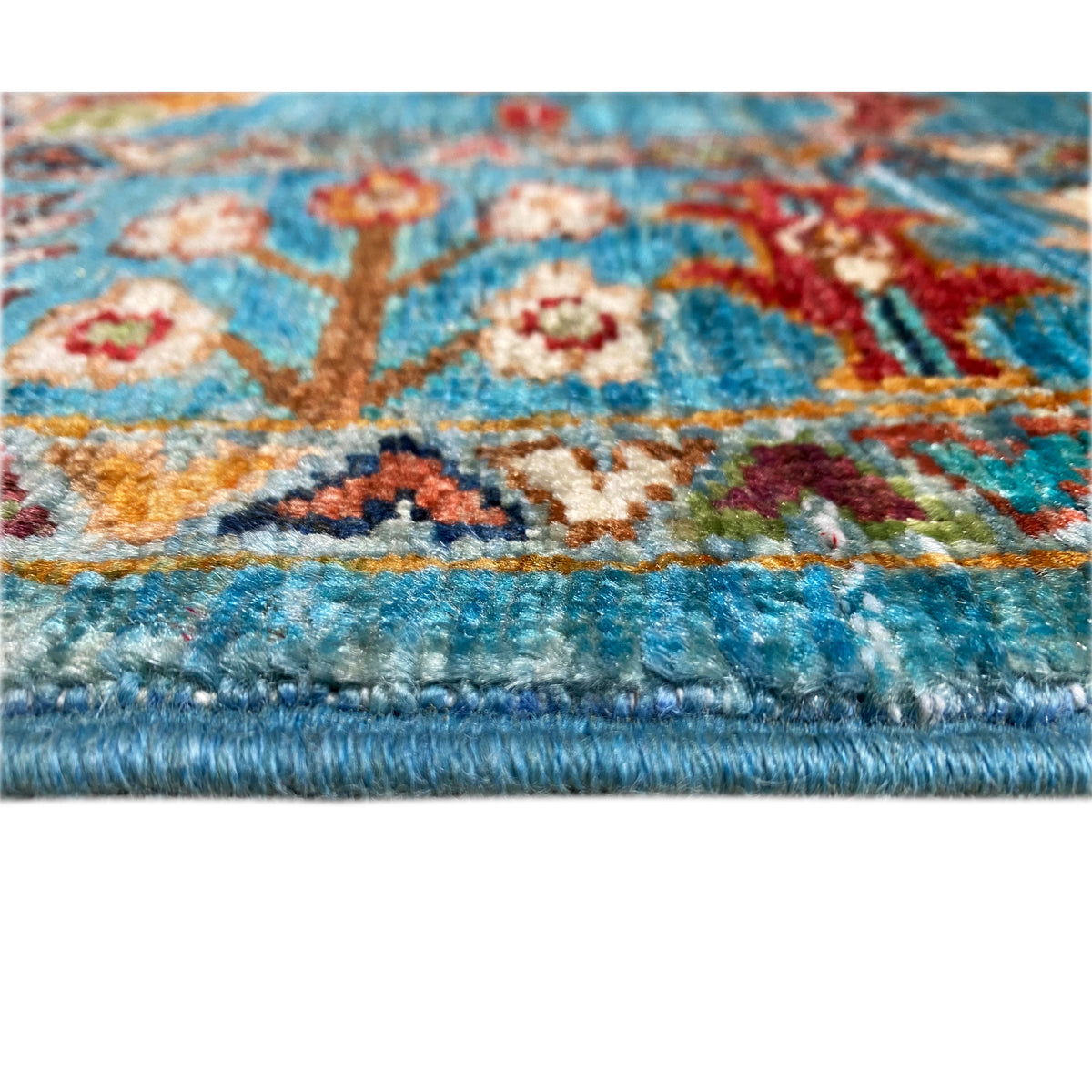 Close-up of the rug edge: blue pattern with colorful ornaments, dense pile