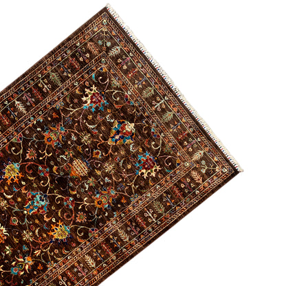 Corner view: Hand-knotted Khorjin rug with an ornamental border and colorful motifs
