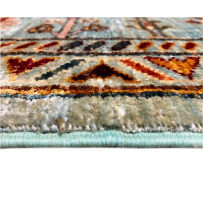 Close-up of the carpet edge: turquoise pile with a bordered pattern and fringes