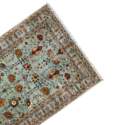 Oblique view of a Khorjin rug with a turquoise background and medallion borders