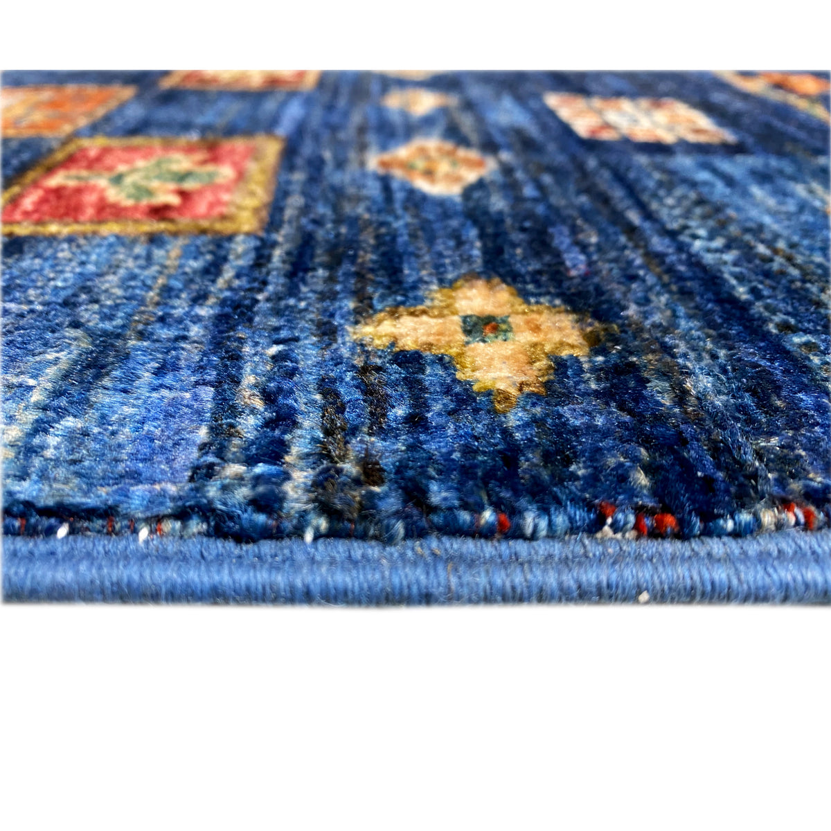 Close-up of the pile and border: blue pattern with yellow and red areas, visible fringes