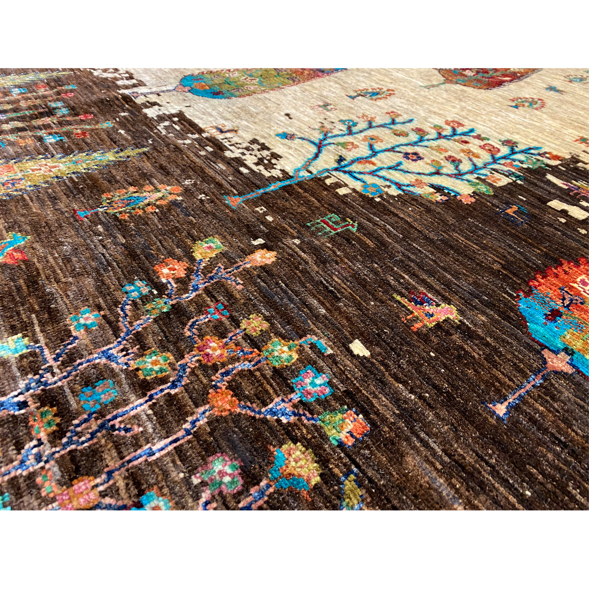 Hand-knotted Khorjin rug detail, brown woven texture with colorful tree and patterned areas
