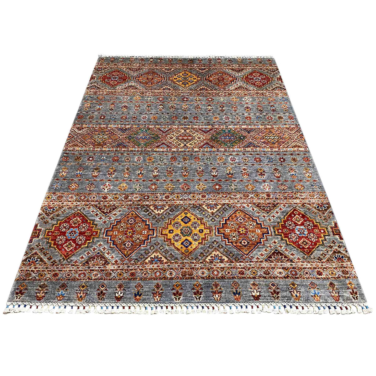 Rectangular rug with a geometric pattern in gray and warm accents, with fringes
