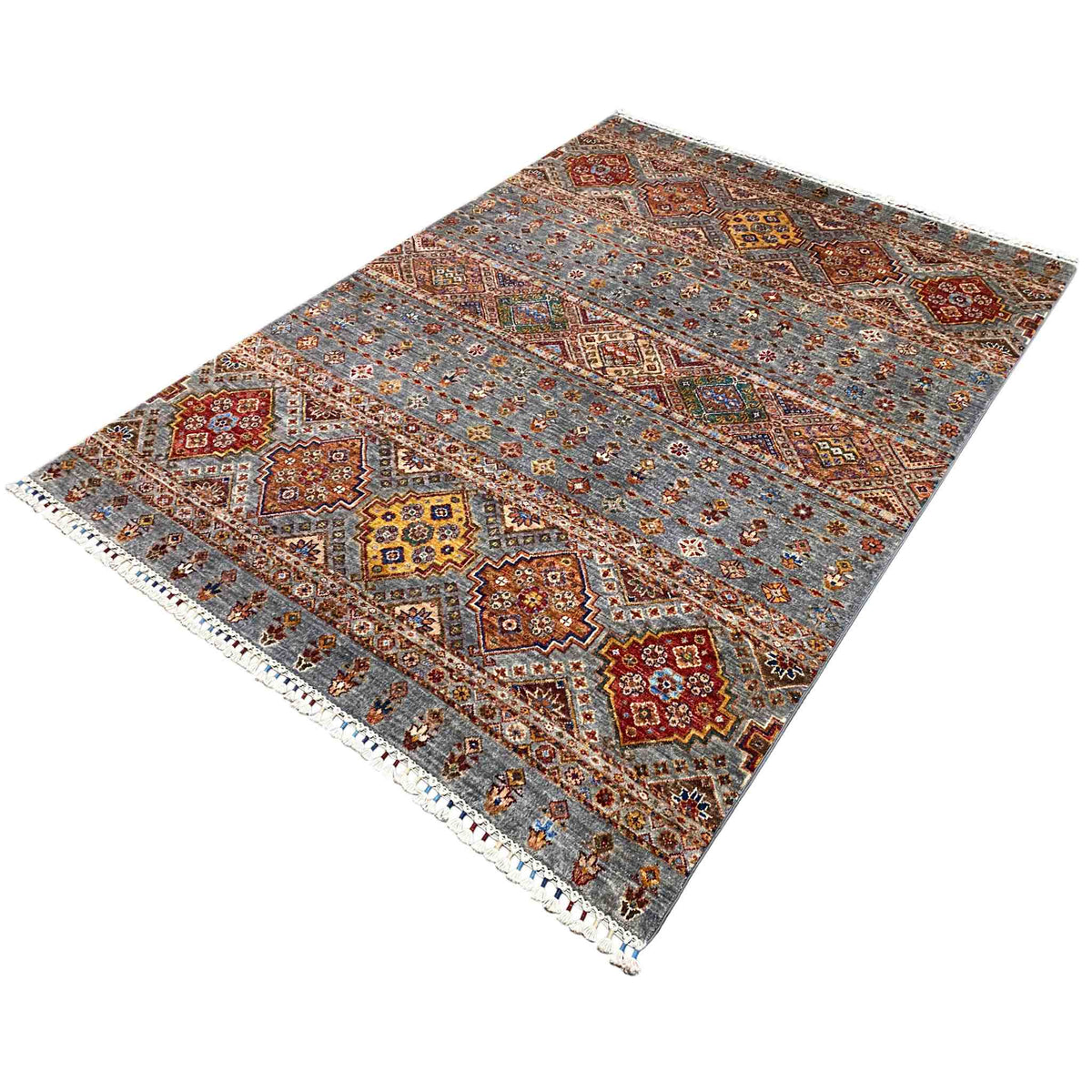 Rug detail view: geometric tribal design in gray, red, blue, and yellow with fringes