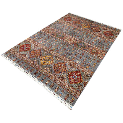 Rug detail view: geometric tribal design in gray, red, blue, and yellow with fringes